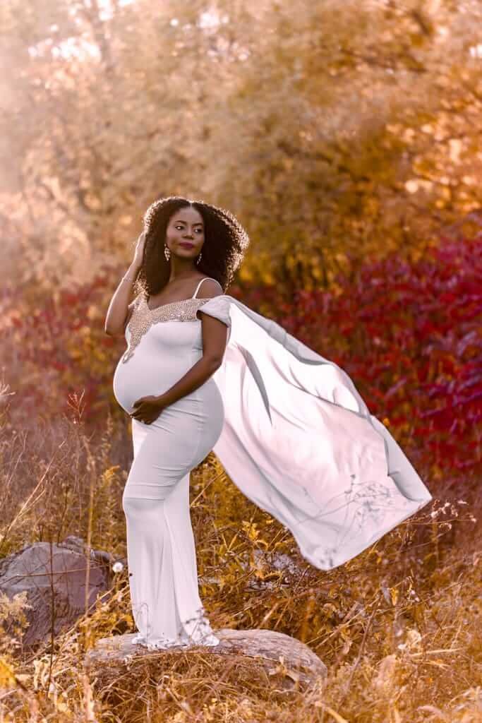 Une femme enceinte vêtue d’une longue robe blanche, photographiée à l'automne par une photographe professionnelle de Granby.