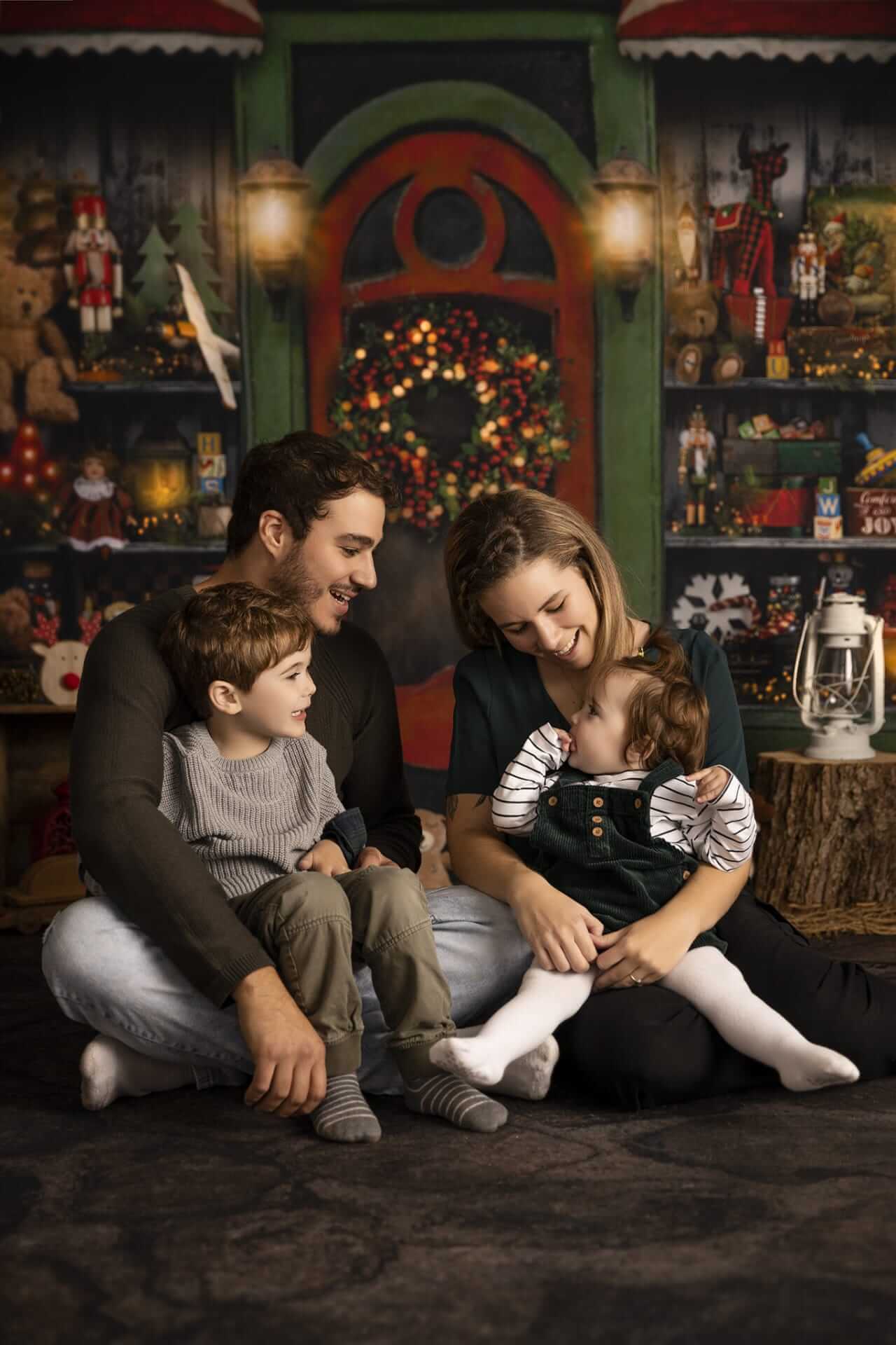 Une famille est assise par terre devant un sapin de Noël.