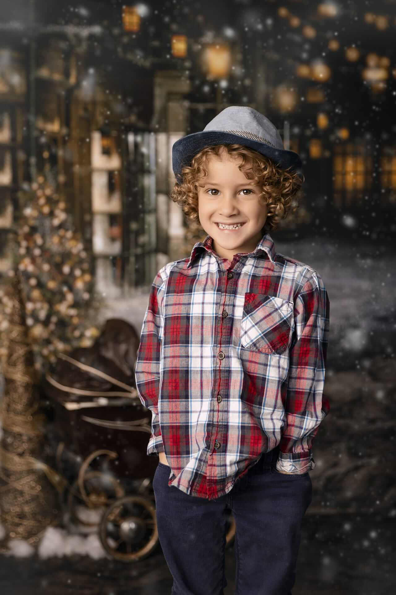 Un jeune garçon portant une chemise à carreaux et un chapeau devant un sapin de Noël.