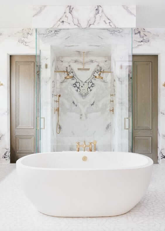 Une salle de bain blanche avec des murs en marbre et une grande baignoire.
