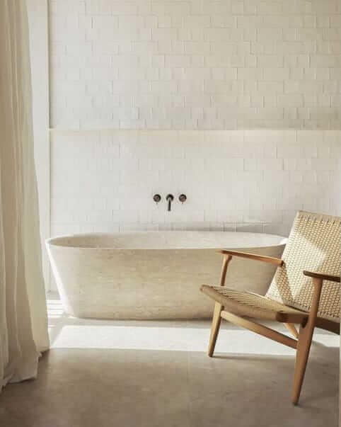 Une salle de bain blanche avec une chaise en bois et une baignoire.