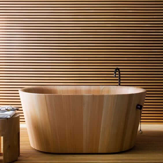 Une baignoire en bois devant un mur en bois.