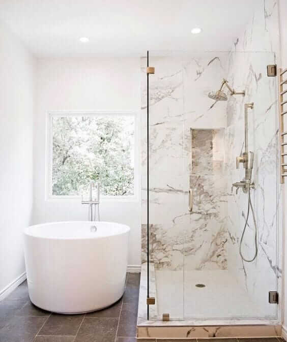 Une salle de bain blanche avec cabine de douche et baignoire en marbre.