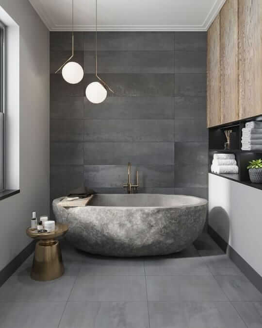 Une salle de bain grise avec une grande baignoire en pierre.