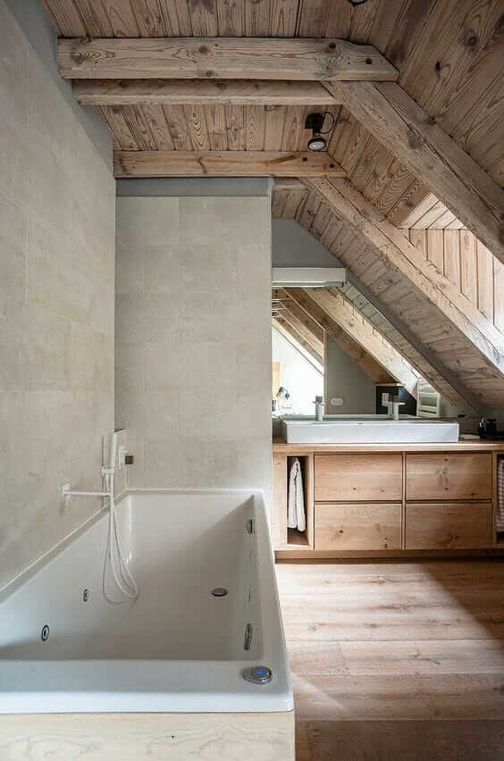 Une salle de bain mansardée avec poutres en bois et baignoire.