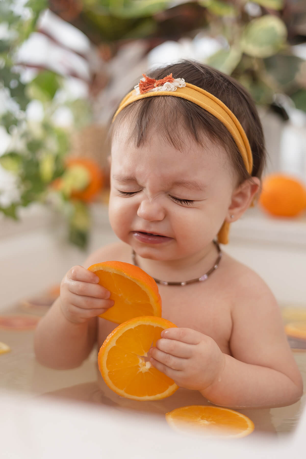 Un bébé dans une baignoire entouré de tranches d'orange, magnifiquement capturé par un talentueux photographe spécialisé dans les portraits d'enfants.