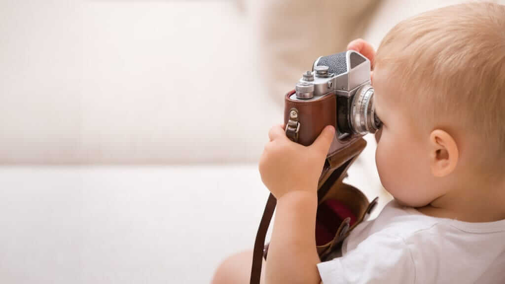 Un bébé s'amuse avec un appareil photo vintage.