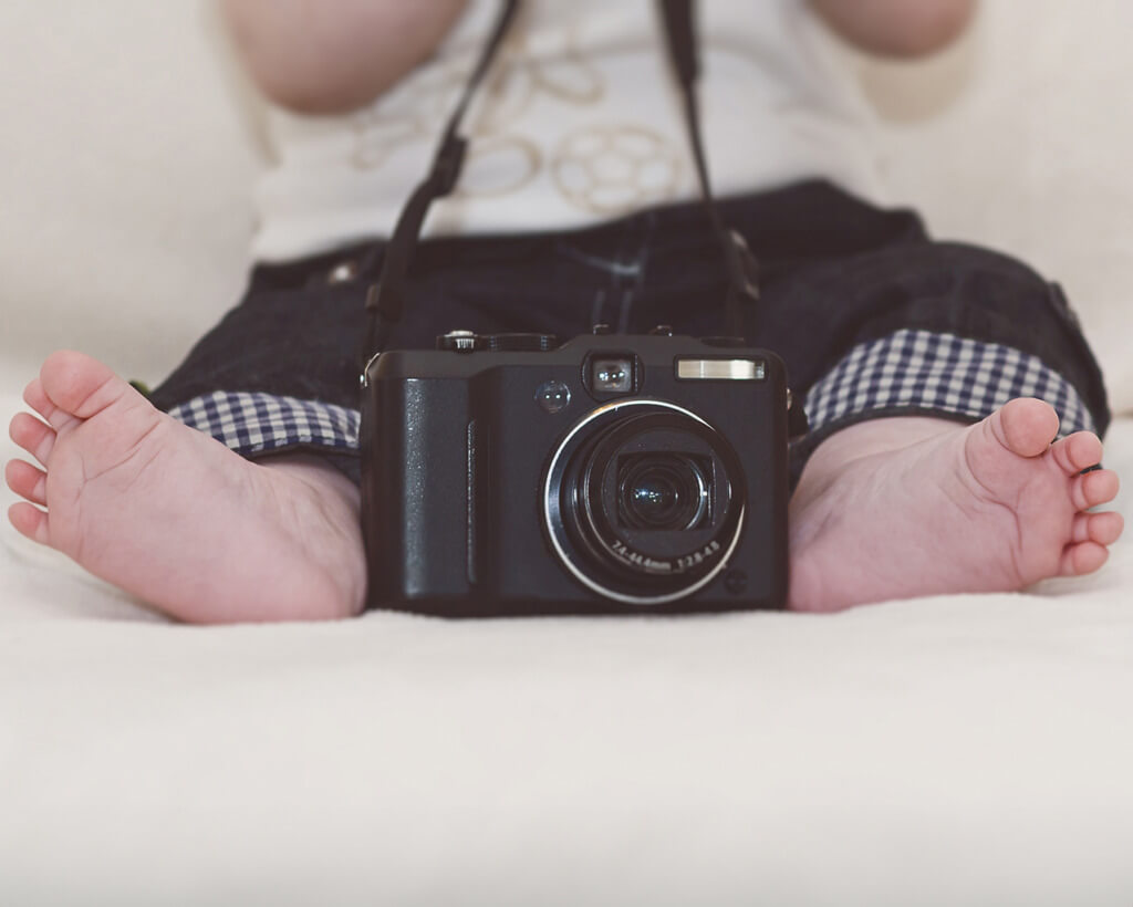 Un bébé assis sur un canapé, capturant des moments avec un appareil photo.