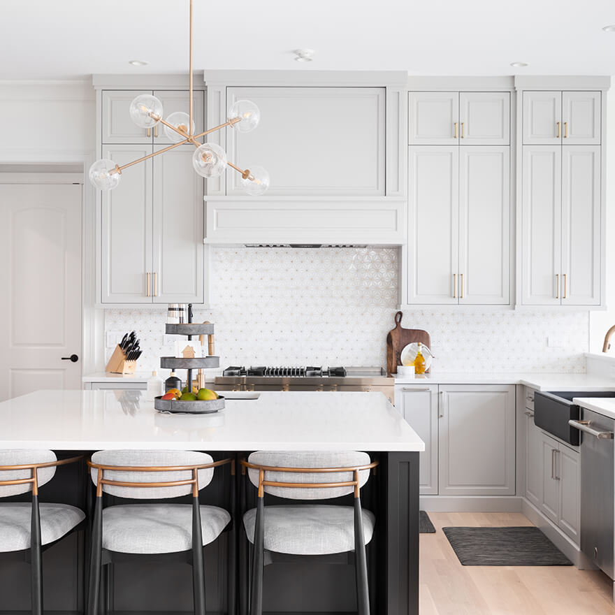 Une cuisine moderne avec armoires blanches et comptoirs noirs, mettant en vedette l'expertise d'un designer d'intérieur.