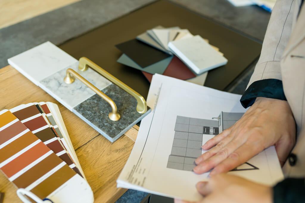 Une designer d'intérieur regarde des échantillons de peinture et des plans sur une table.