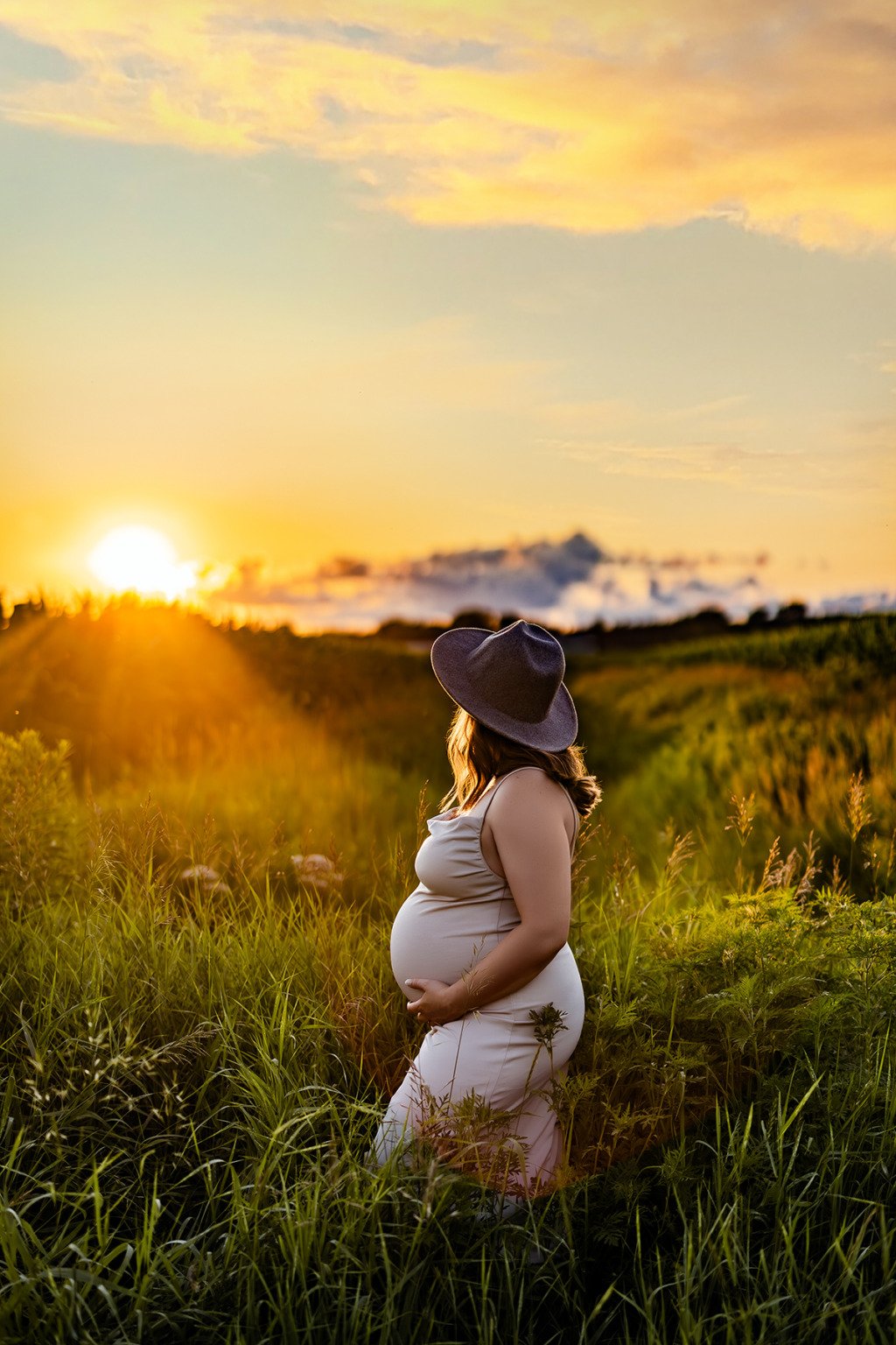 Une femme enceinte debout dans un champ au coucher du soleil — Rébecca Vandal, photographe à Granby