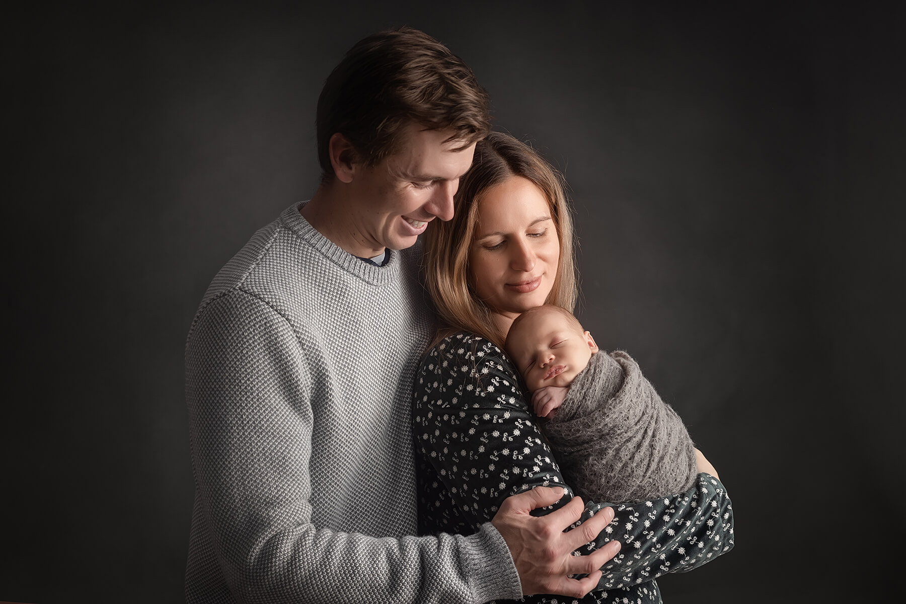 Un couple berce son précieux nouveau-né tout en se faisant photographier par un photographe de studio professionnel.