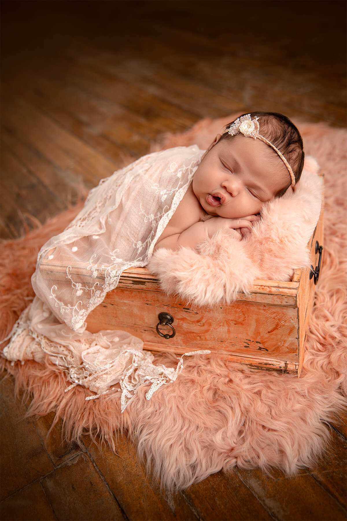 Un nouveau-né dormant dans une boîte en bois sur un plancher en bois.
