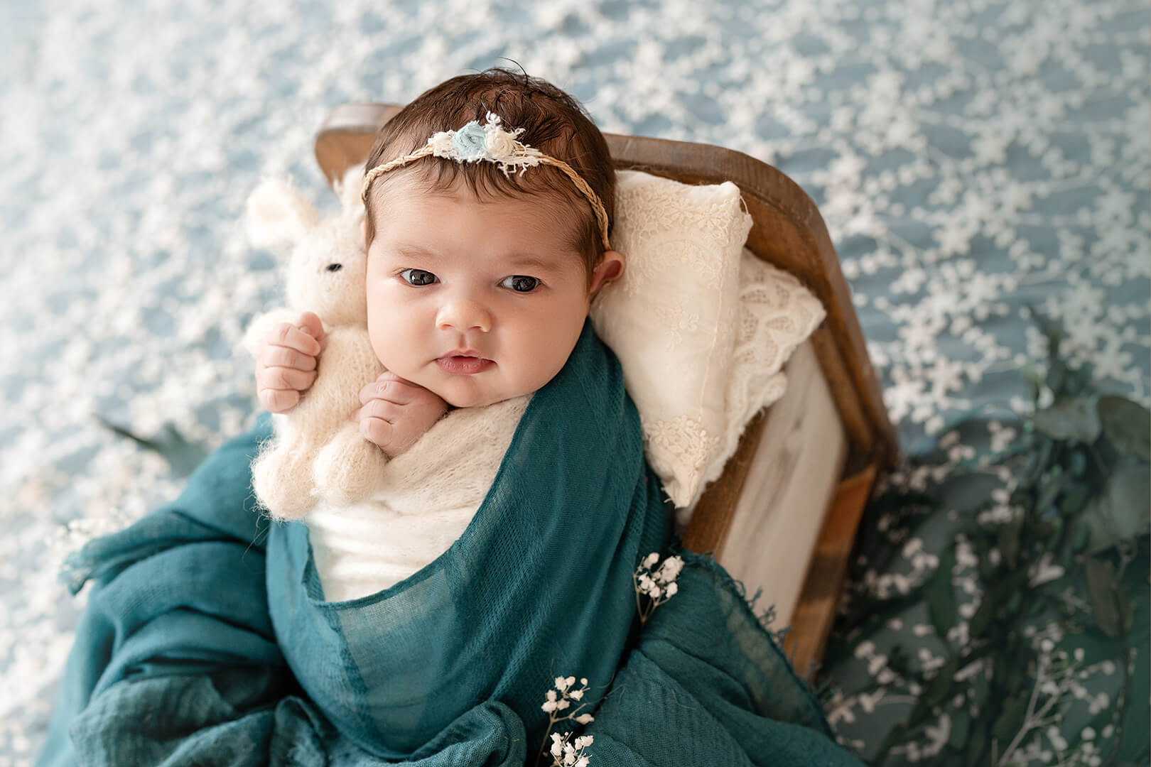 Un bébé fille portant un emmaillotage de couleur bleu vert, lors d'une séance photo nouveau-né à Granby.