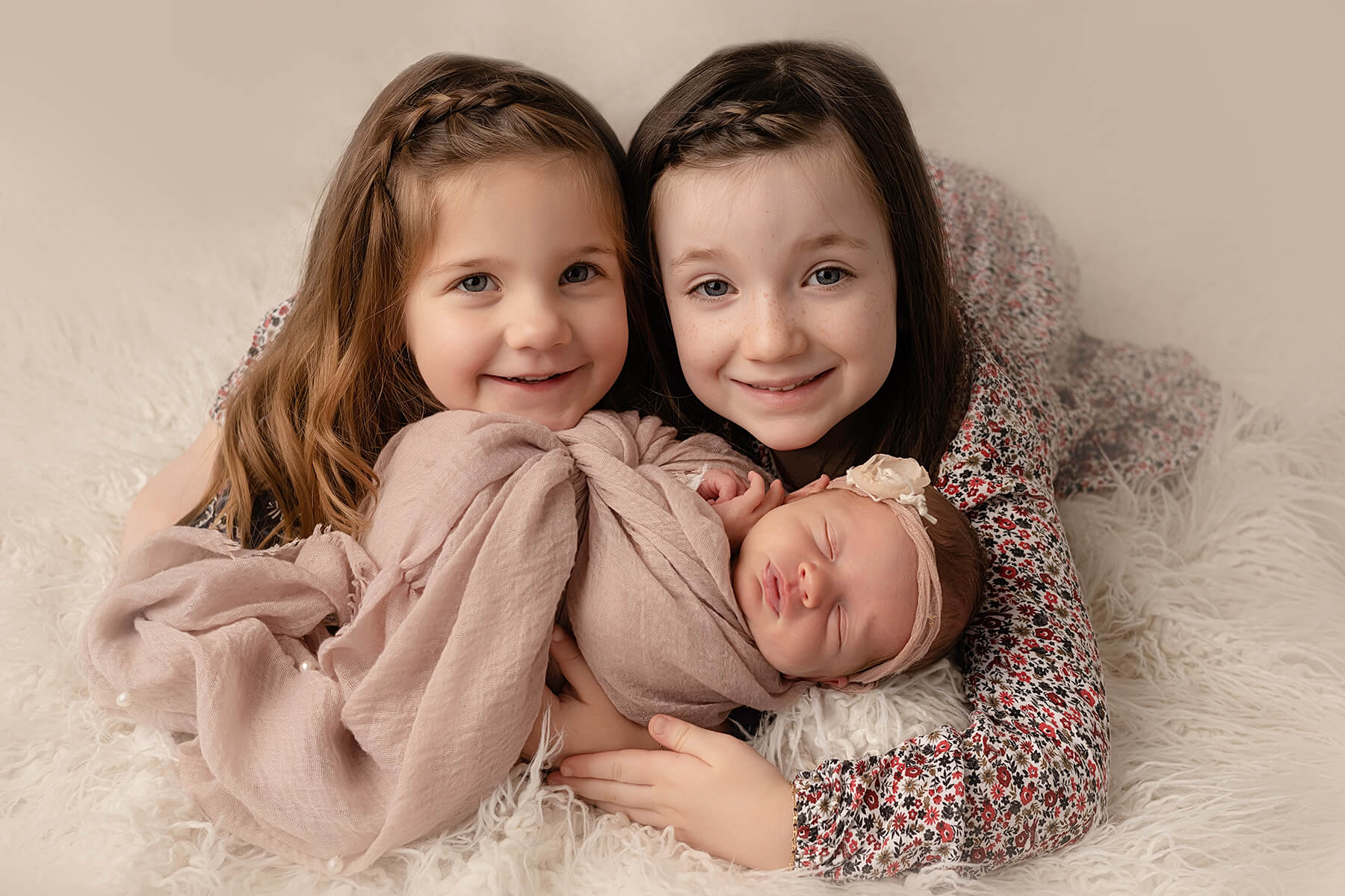 Trois petites filles posant pour une photo de famille lors d'une séance nouveau-né à Granby.