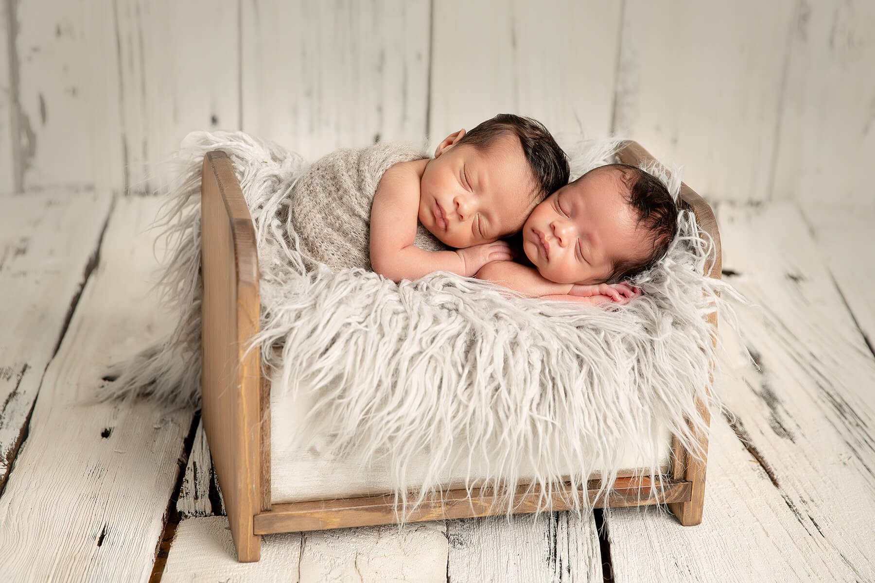 Deux bébés nouveau-nés paisiblement endormis dans une boîte en bois lors d'une séance photo à Granby.
