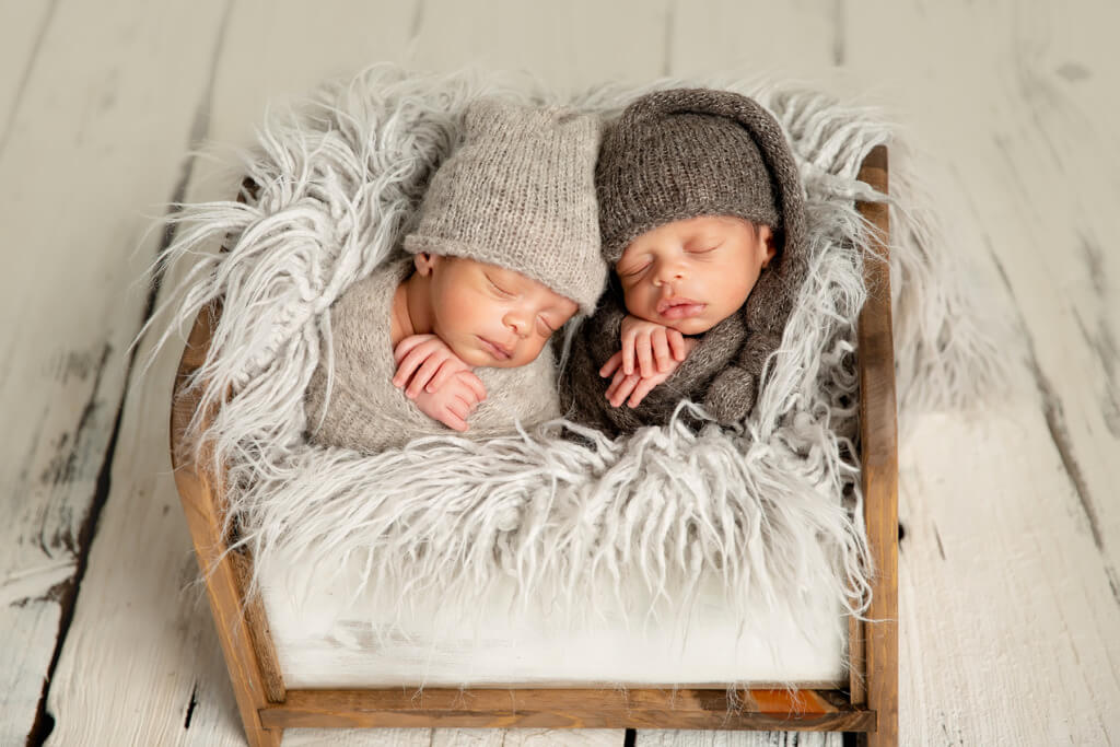 Deux nouveaux-nés jumeaux dormant dans un berceau en bois lors d'une séance photo à Granby.