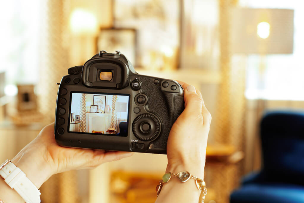 Une designer d'intérieur photographiant un salon à Granby avec son appareil photo.