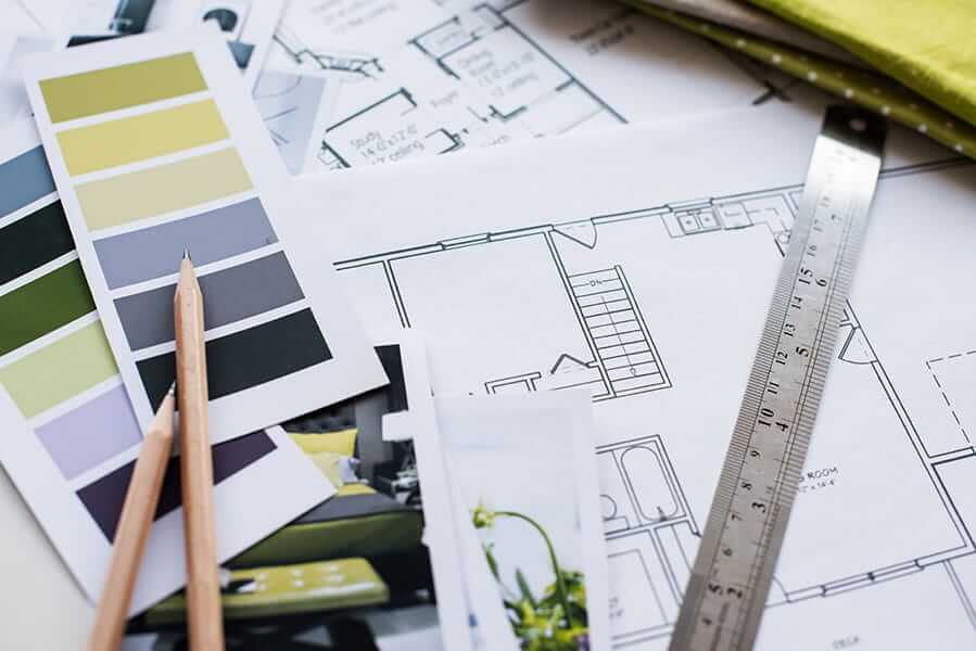 Un designer d'intérieur à Granby crée un croquis méticuleux et détaillé d'une maison, à l'aide de règles et de crayons pour des mesures précises et une représentation impeccable.