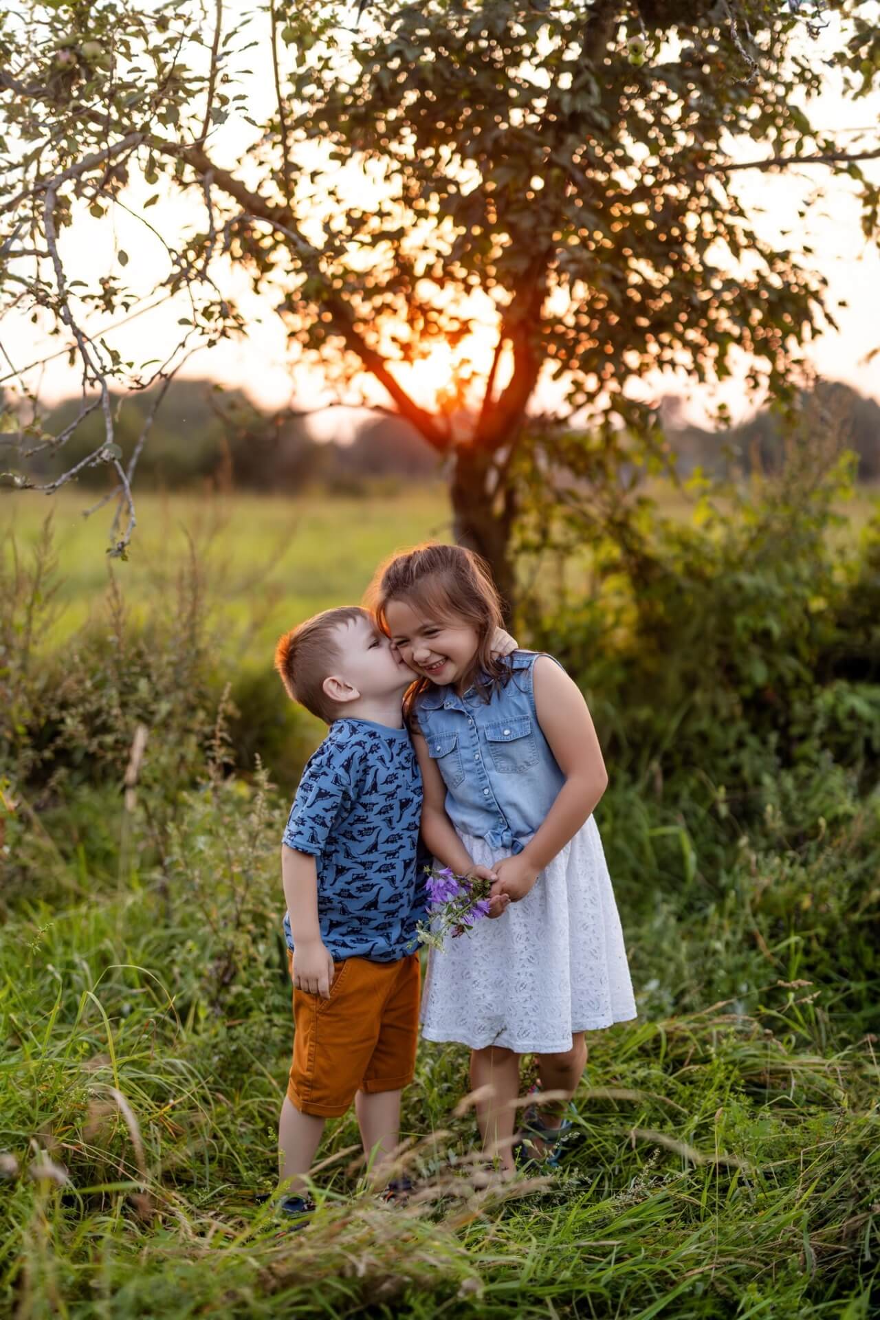 Deux enfants s'embrassant dans un champ au coucher du soleil.