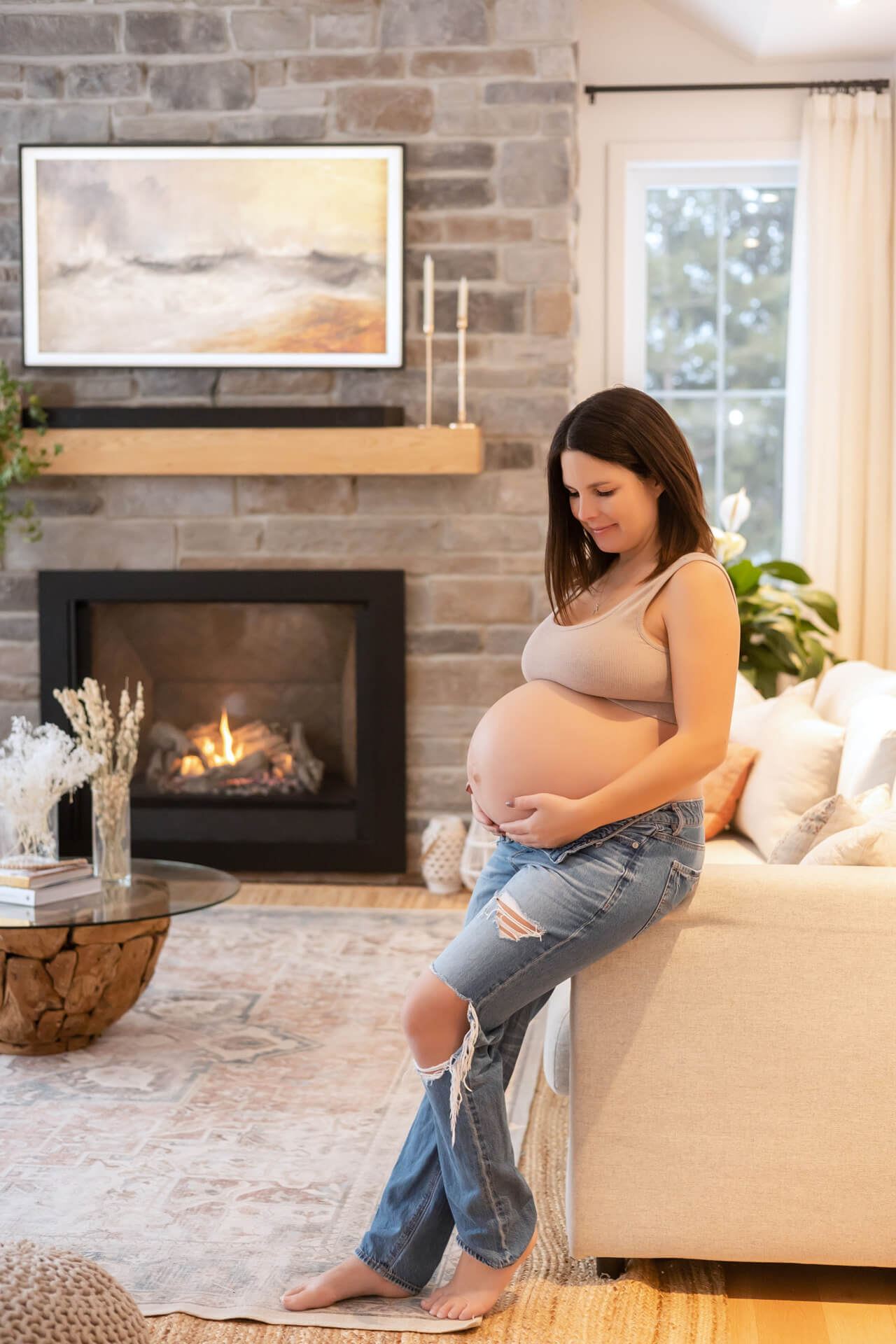 Une femme enceinte assise sur un canapé devant une cheminée.