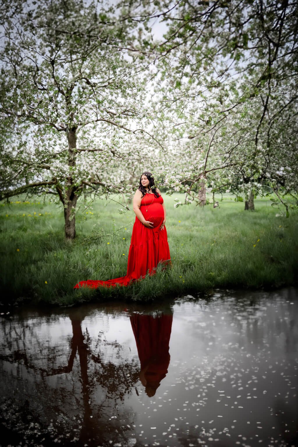 Une femme enceinte vêtue d’une robe rouge debout dans un étang — Rébecca Vandal, photographe à Granby