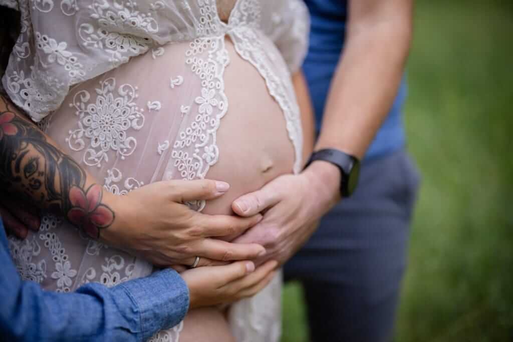Une femme enceinte est tenue par son mari, tandis qu'un photographe capture ce moment d'émotion — Rébecca Vandal, photographe à Granby