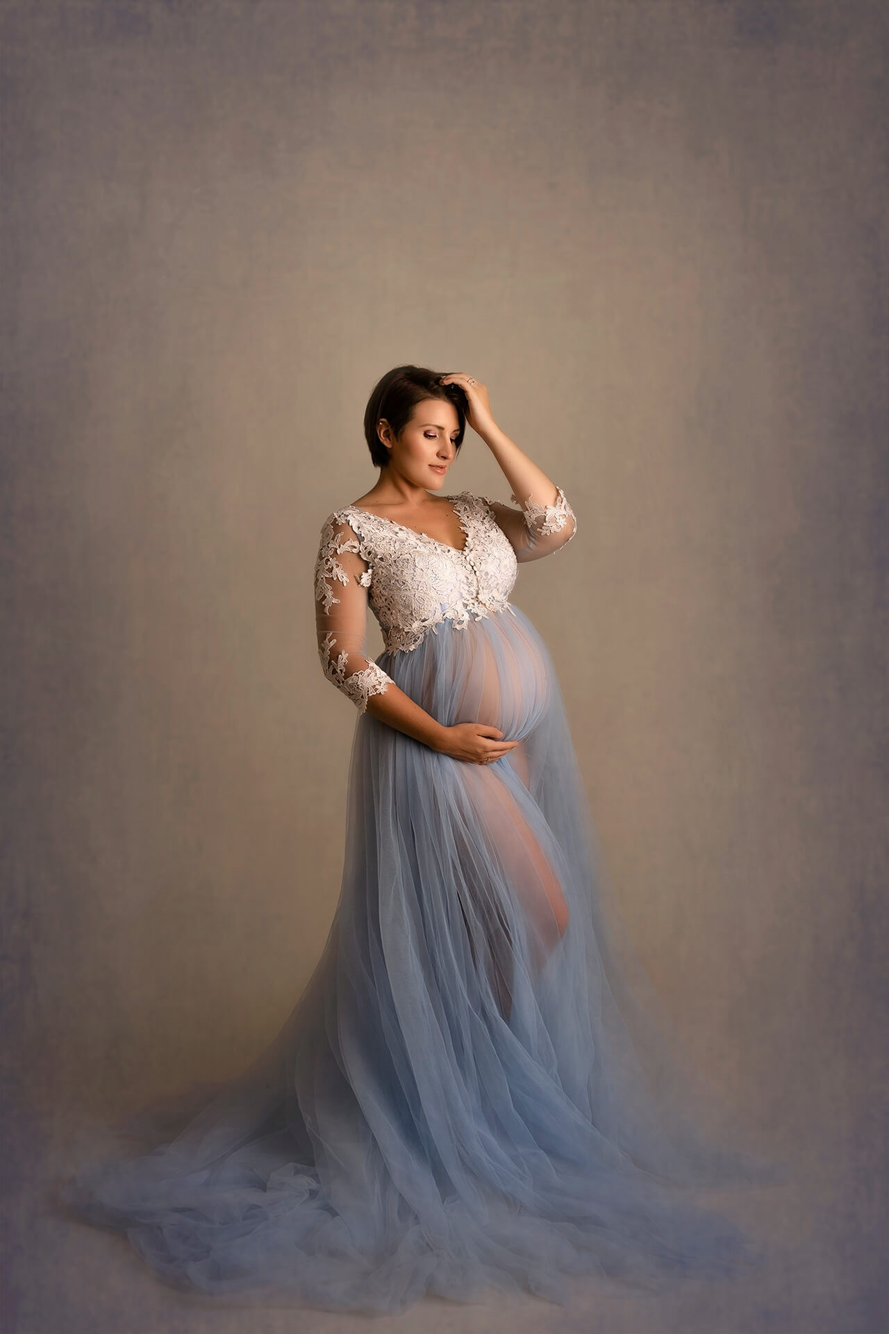 Une femme enceinte vêtue d'une robe en tulle bleu posant pour une photo.
