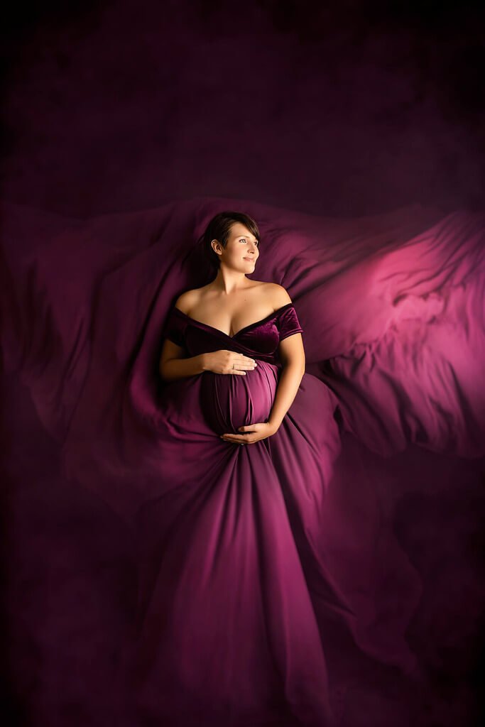 Une femme enceinte posant dans une robe violette.