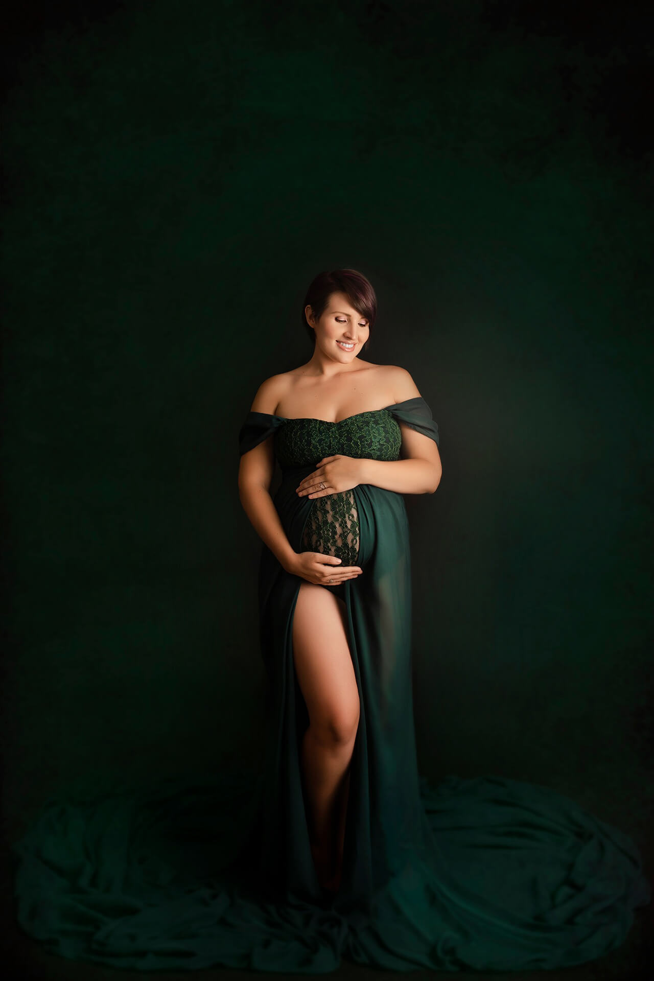 Une femme enceinte vêtue d'une robe verte posant pour une photo.