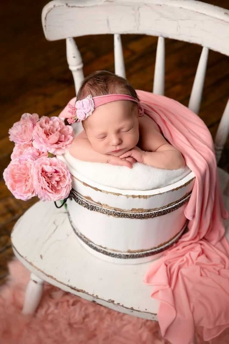 Un bébé dormant dans un seau rose avec des fleurs roses