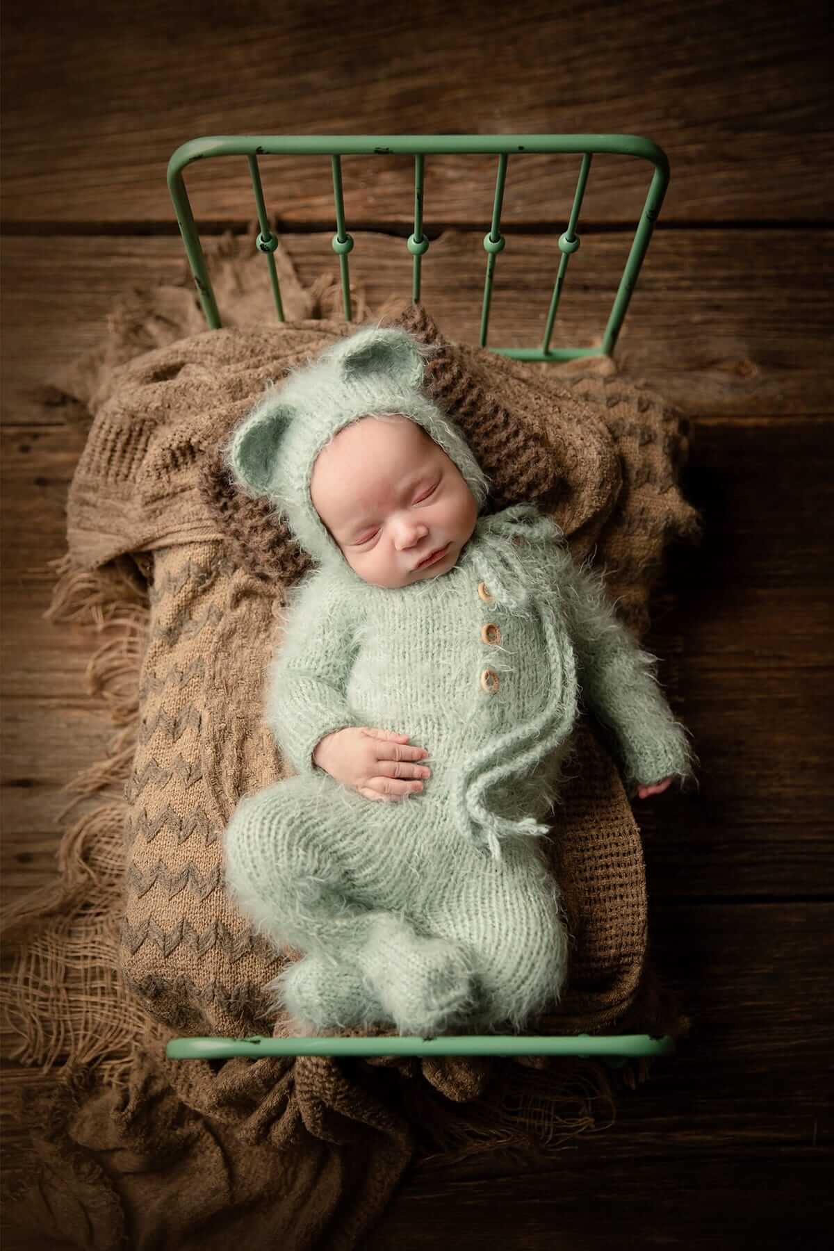 Un nouveau-né en tenue d'ours vert, photographié par une photographe de Granby.