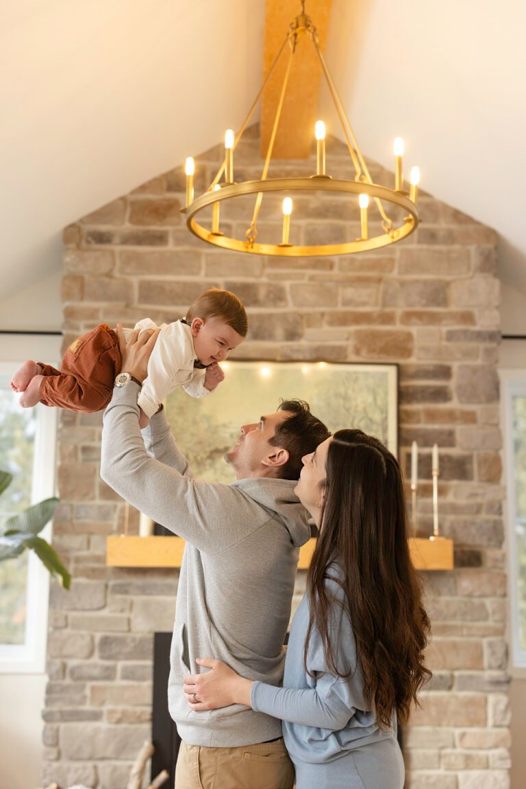 Papa qui soulève son bébé dans le salon familial