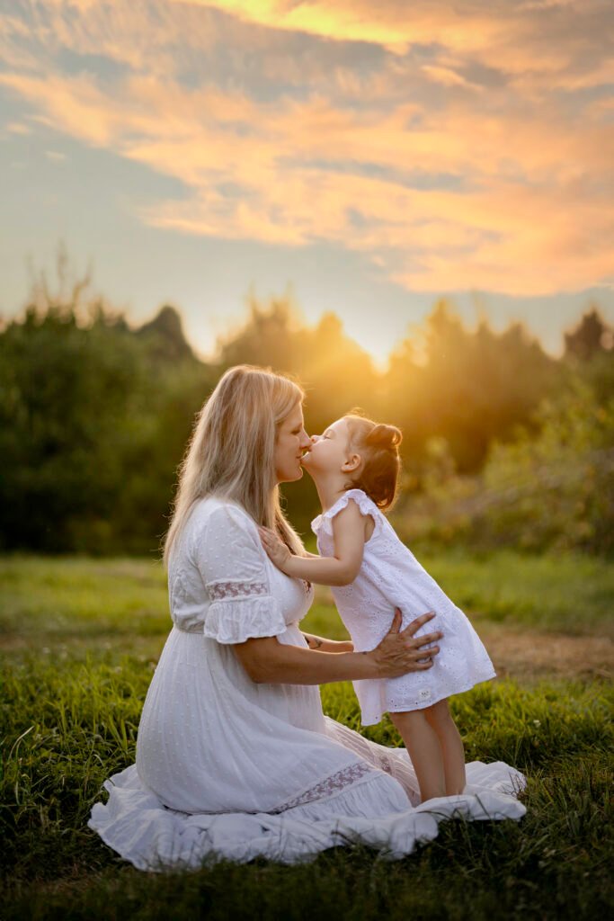 Maman à genoux qui embrasse sa fille au coucher du soleil