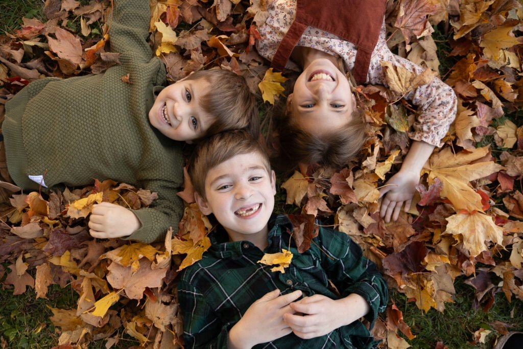 Trois enfants couchés dans les feuilles d’automne — Rébecca Vandal, photographe à Granby