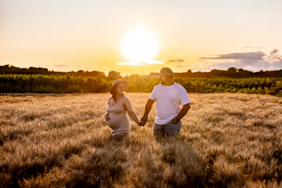 Couple main dans la main dans un champ au coucher du soleil, séance maternité — Rébecca Vandal, photographe à Granby