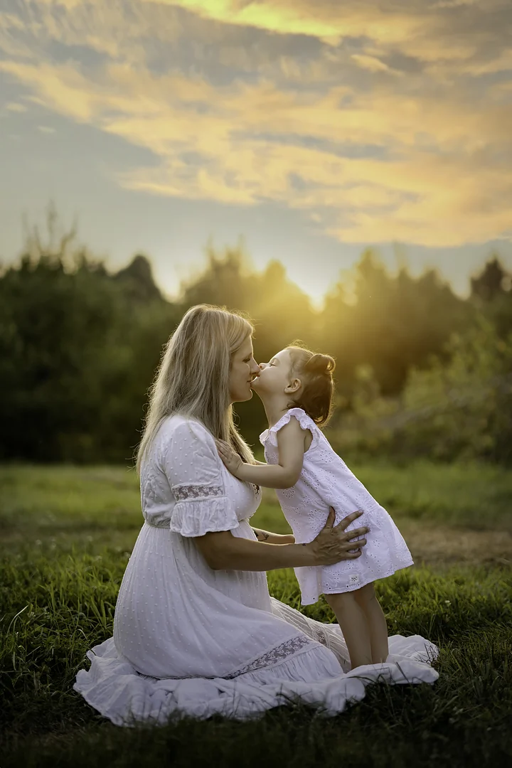 Maman à genoux qui embrasse sa fille au coucher du soleil