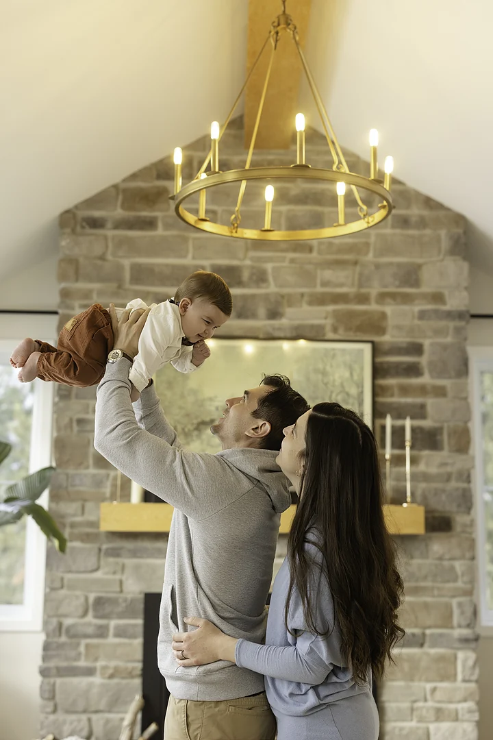 Papa qui soulève son bébé dans le salon familial