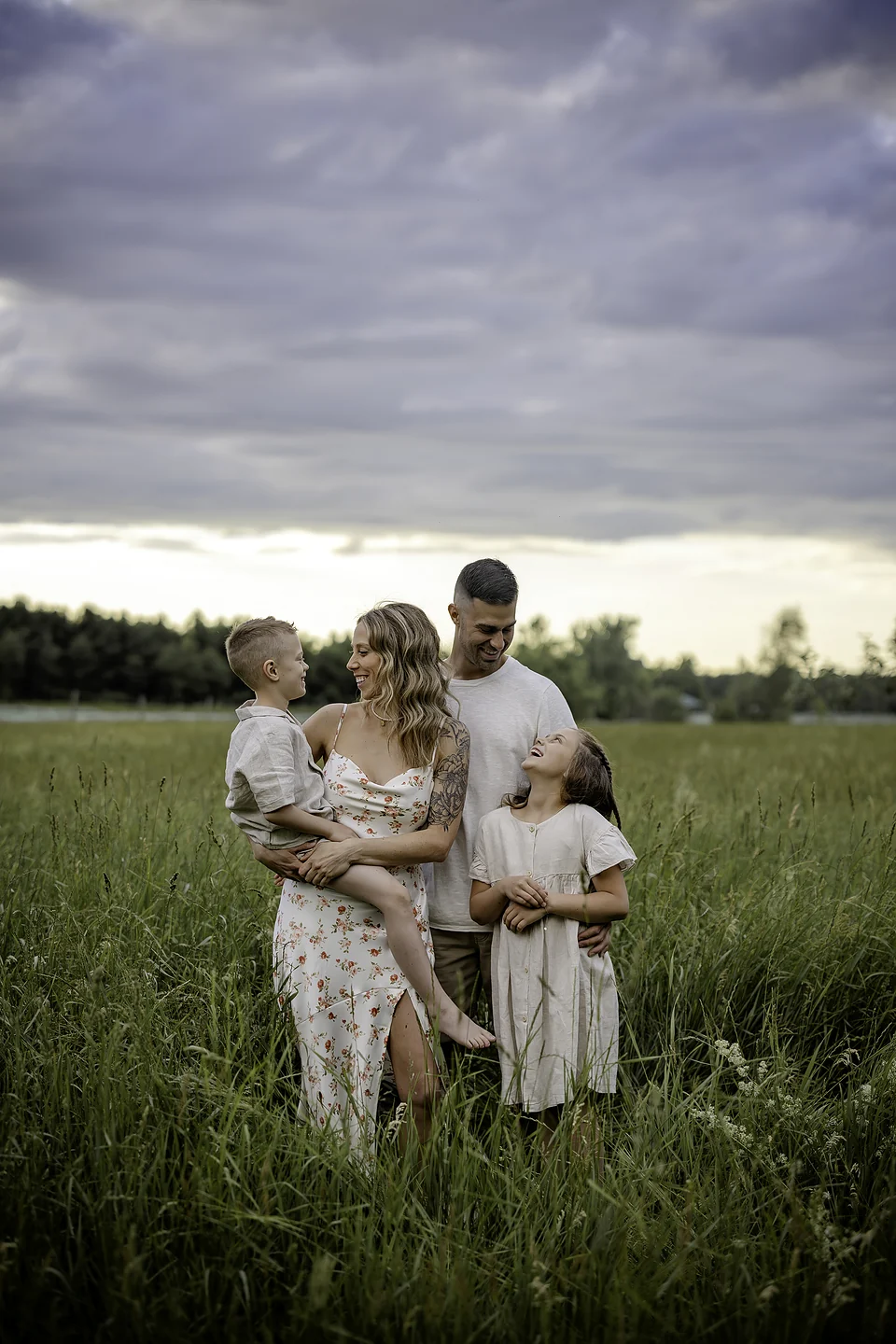 Famille de quatre dans un champ sous un ciel d’été — Rébecca Vandal, photographe à Granby