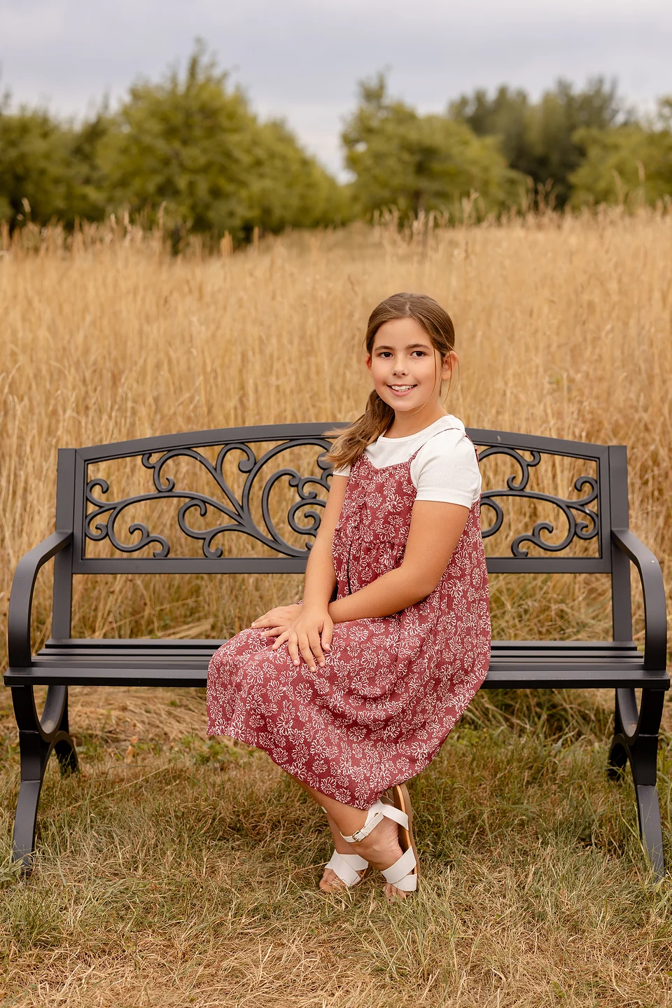 Jeune fille en robe fleurie assise sur un banc dans un champ — Rébecca Vandal, photographe à Granby