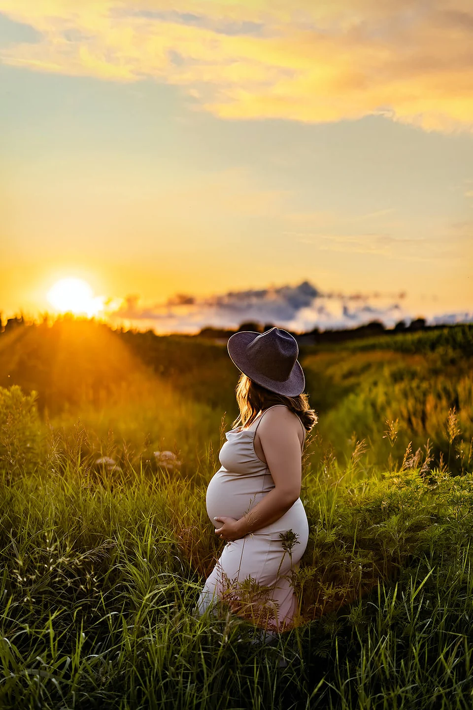 Une femme enceinte debout dans un champ au coucher du soleil — Rébecca Vandal, photographe à Granby