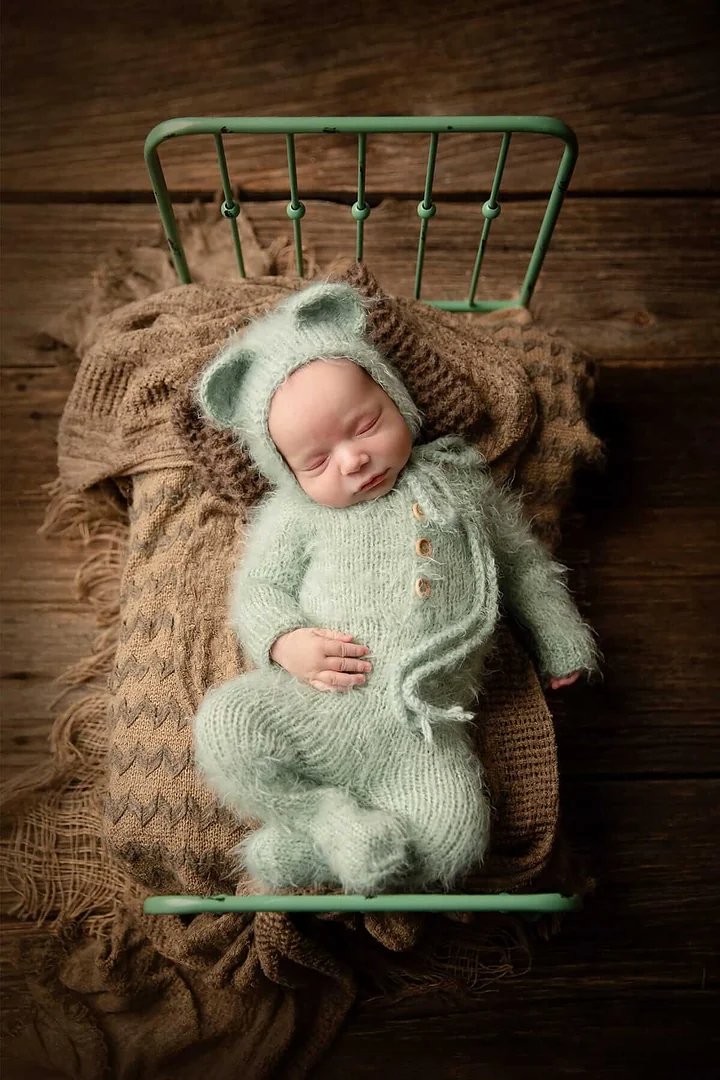 Un nouveau-né en tenue d'ours vert