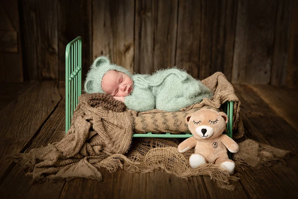 Un bébé dort dans un lit en métal avec un ours en peluche — Rébecca Vandal, photographe à Granby