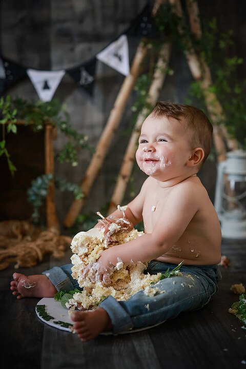 Un bébé joue avec un gâteau devant une tente.