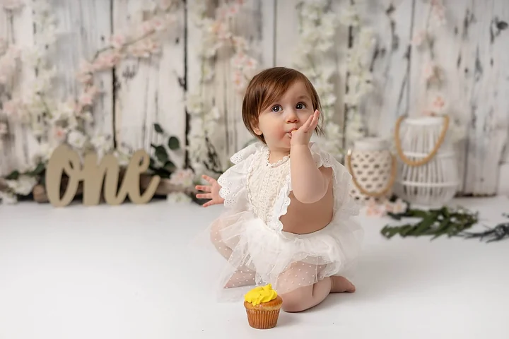 Une petite fille assise par terre avec un cupcake devant elle