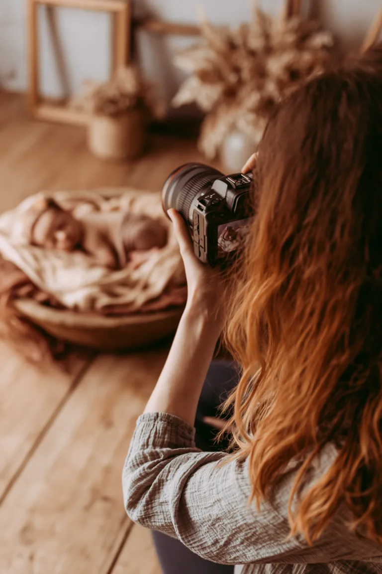 Une photographe réalise une prise de vue d’un nouveau-né dans un décor aux tons naturels.